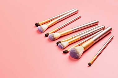 Pembe arka planda kozmetik makyaj fırçaları. Düz konum, üst görünüm, kopyalama alanı. Makyaj aksesuarları, model, şablon.
