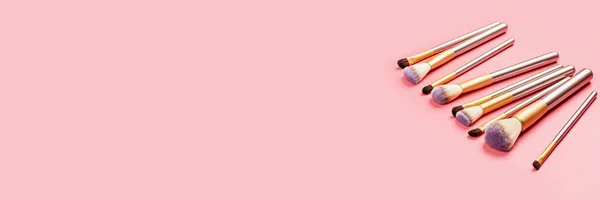 Pinceles de maquillaje sobre fondo rosa. Acostado plano, vista superior, arriba. Banner largo horizontal para diseño web — Foto de Stock