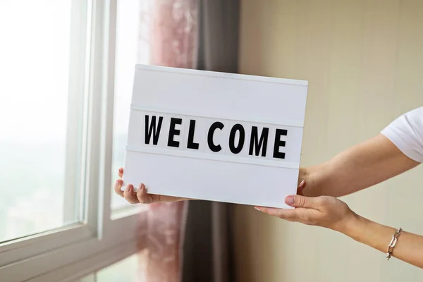 Woman holding lightbox with word Welcome in hands. End of covid-19 quarantine. Hotel, restaurant, cafe, local shop, service owner welcoming guests after coronavirus outbreak and people shutdown