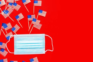 4 Temmuz. Kırmızı arka planda ABD bayrakları ve tıbbi maske. Amerika 'nın Bağımsızlık Günü 2020 Coronavirus covid-19 pandemik karantinası sırasında. Düz konum, üst görünüm, şablon.