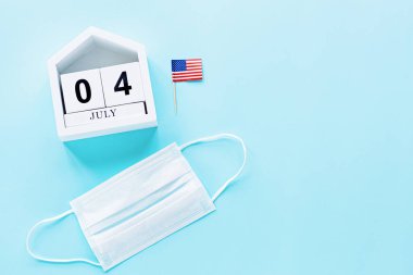 4 Temmuz. Mavi arka planda ABD bayrağı ve tıbbi maske. Amerika 'nın Bağımsızlık Günü 2020 Coronavirus covid-19 pandemik karantinası sırasında. Düz konum, üst görünüm, şablon.