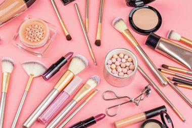 Pembe arka planda kozmetik ürünler. Düz yatış, üst görünüm