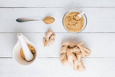 Doğal zencefil, zencefil tozu, havan topu ve masada kaşık.