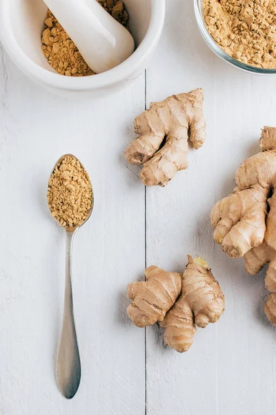Natural ginger, ginger powder, mortar with chopped ginger and a spoon on the table — Stock Photo, Image