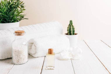 Kaplıca ve kişisel bakım eşyaları yumuşak renklerle dolu bir odada, ahşap bir masanın üzerine yerleştirilmiş.