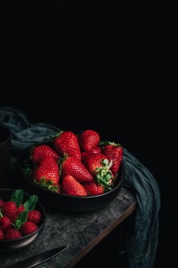 Bir kase çilek, bir kase ahududu ve yıpranmış masanın köşesinde antika bir paçavra ile sakin bir hayat.