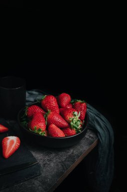 Bir kase çilek ve yıpranmış masanın köşesinde bıçakla dolu bir kesme tahtasıyla hayat