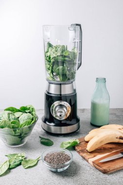 Masada ıspanaklı içecek yapmak için blender ve malzemelerle dolu bir hayat. Mikser ıspanakla dolu.