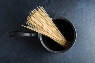 Kırsal, mavi, yıpranmış bir masanın üstünde spagetti olan küçük bir tencere. Geleneksel İtalyan mutfağı kavramı. Moody tarzı