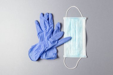 Gri arka planda mavi tıbbi eldiven ve tıbbi maske..