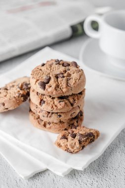 Peçetelere çikolata parçacıklı kurabiye yığını, bir fincan çay ve bir gazete. Temiz biçim