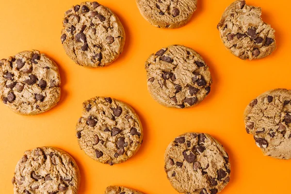 Chocolate chip cookie pattern on orange background, top view