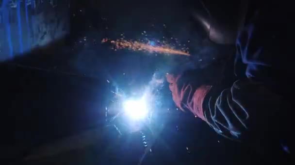 Человек в специальном комбинезоне сваривает арматурные элементы на заводе — стоковое видео