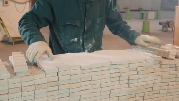 Factory worker in jumpsuit gathers white concrete bricks — Stockvideo