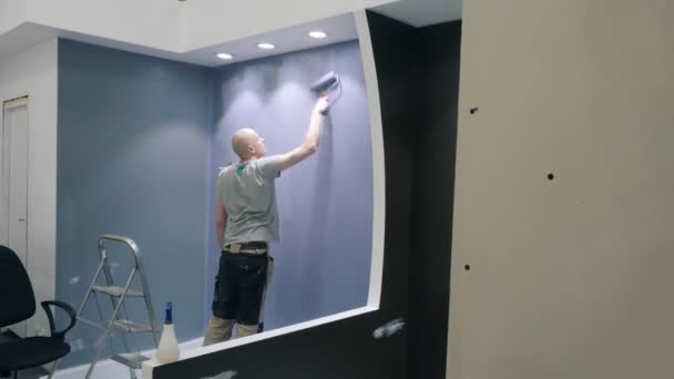 Trabajador lleva a cabo la reparación de la pared de pintura con tinte lila — Vídeos de Stock
