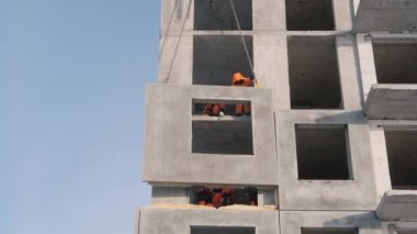 İşçiler duvar panelleri kurmak için çok katlı binalar inşa ediyorlar.