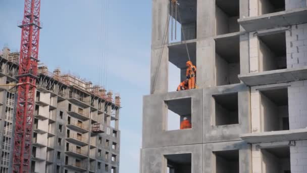 İnşaatçılar, vinçle kaldırılan beton duvar panelleri monte ediyorlar. — Stok video
