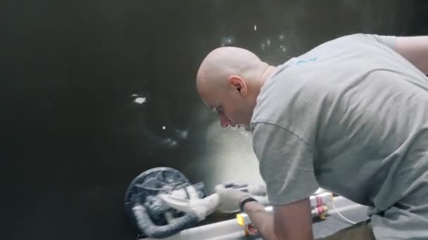Парень делает ремонт квартиры с помощью шлифовального станка с пылесосом — стоковое видео
