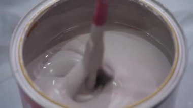 Birisi matkabı kırmızı başlıkla tutar ve kahverengi boyayı karıştırır.