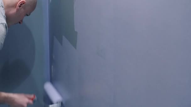 Работник отделки стены в фиолетовый цвет с помощью ролика — стоковое видео