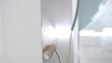 Boyacı beyaz düz duvarı kahverengi boyayla kaplıyor.