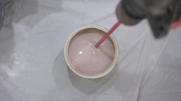 Worker mixes brown paint with special drill nozzle in bucket — Stock Video