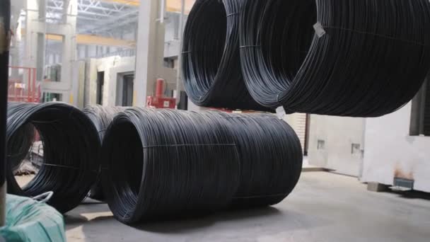 Crane puts large black rebar hanks of wire on shop floor — Stock Video