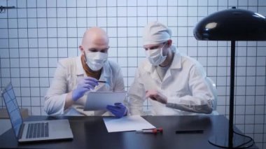 Erkekler Coronavirus araştırma laboratuarındaki testlerin sonuçlarını kontrol ederler.