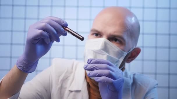 Лаборант в перчатках и маске держит образец коронавируса — стоковое видео