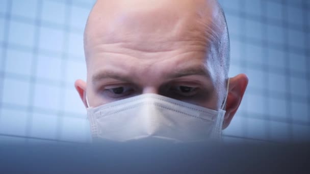 Man i mask fungerar på datorn studerar coronavirus infektion — Stockvideo