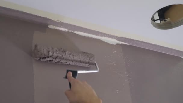 Entrepreneur peint mur avec brosse à rouleaux près du plafond de la pièce — Video