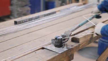 Fabrika işçisi özel metal aletlerle uzun demir çubuk tellerini eğdi