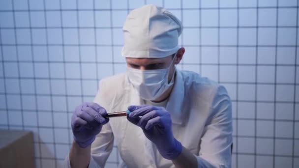Assistent in Uniform schaut sich Blutprobe mit Coronavirus an — Stockvideo