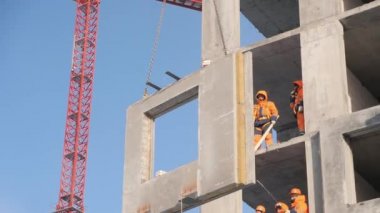 Erkekler vinç tarafından kaldırılan beton panel kurulumuna katıldılar