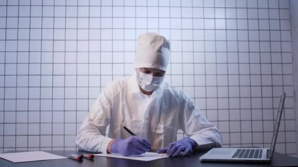 Lekarz pisze raport o testach koronawirusowych przy stole — Wideo stockowe