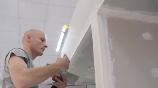 Builder carries out client order smoothing out puttied walls — Stock Video