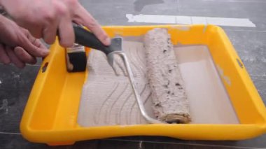 Becerikli usta, özel sarı tepside tekerlekli fırçayı hareket ettiriyor.