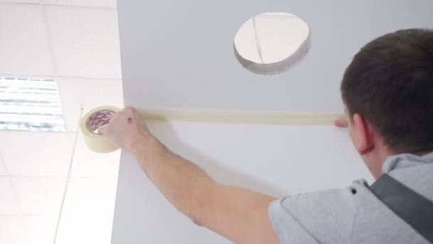 Handwerker klebt gelbes Klebeband an weiße Decke — Stockvideo