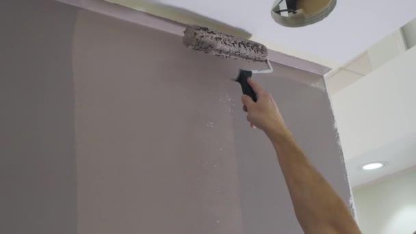Férfi kéz fogja fém görgő ecset és színek szoba fal — Stock videók