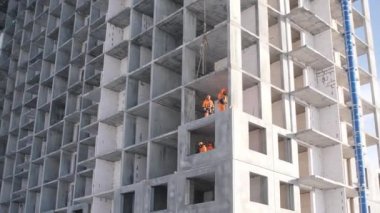 İnşaatçılar binanın zemininde durmuş askıya alınmış panelleri monte ediyorlar