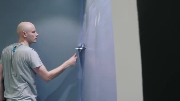 Ремонтник фарбує стіну спальні фіолетовим кольором, уникаючи отвору — стокове відео