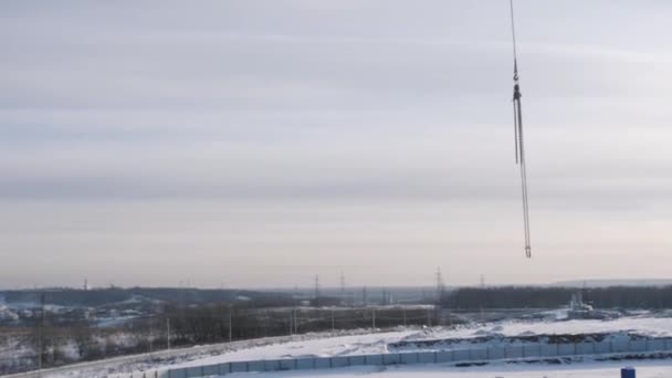 Truck kraan beweegt schorsing boven besneeuwde bouwplaats — Stockvideo