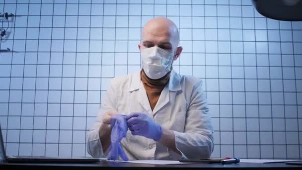 Man in mask puts on gloves in coronavirus researching lab — Stockvideo