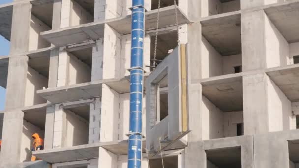 Grúa torre mueve panel de hormigón acercando a los constructores — Vídeos de Stock