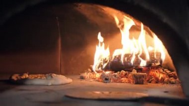 Pizzacı şef mantarlı hamuru tahta kütüklere yaklaştırır.