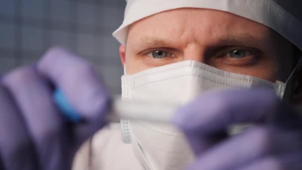 Man i mask håller provrör med etikett coronavirus i lab — Stockvideo