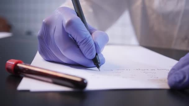Naukowiec pisze raport na temat koronawirusu przy zamknięciu stołu — Wideo stockowe