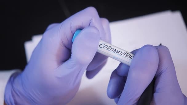 Asistente en guantes morados con muestra de coronavirus en la mesa — Vídeo de stock