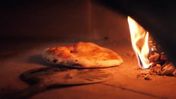 Cook rotates tasty baked pizza and holds above fire flame — Stock Video