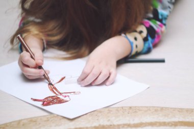 Bir kız çocukluk fantezilerini keçeli kalemlerle kağıda çizer..